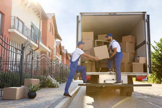 Workers unloading boxes from van outdoors. Moving service - Powered by Adobe