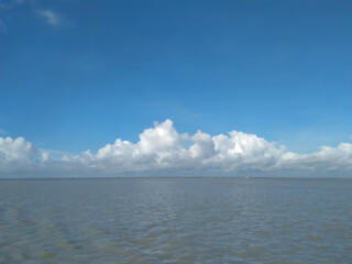 Huge expanse of river, blue sky and raft of white clouds
