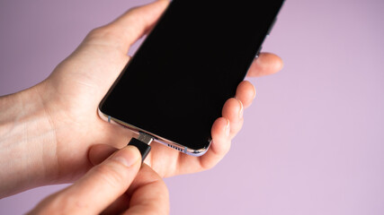 Hand plug-in type-c cable into mobile phone to charge. Smartphone battery charging. Fast charge...