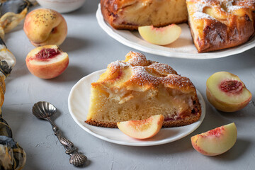 Sliced peach pie sprinkled with powdered sugar on light gray table