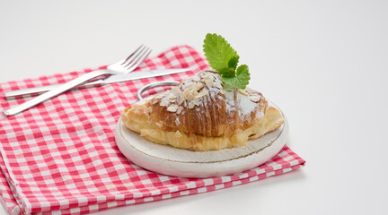Baked croissant sprinkled with sugar on wooden board, red napkin