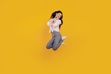 Obraz premium Portrait of adorable positive girl jump posing on yellow background