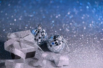 Christmas background, template for New Year greetings - shiny gift box with ribbon and bow on a abstract glitter background with defocused lights in the shape of snowflakes. Selective focus.