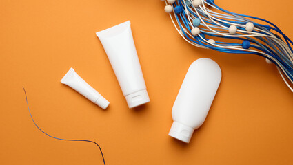 empty white plastic tubes for cosmetics on orange background. Packaging for cream, gel, serum, advertising and product promotion