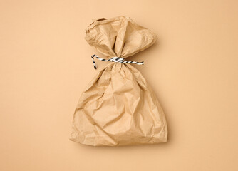 full brown paper disposable food bag on a beige background, concept of delivery and ordering