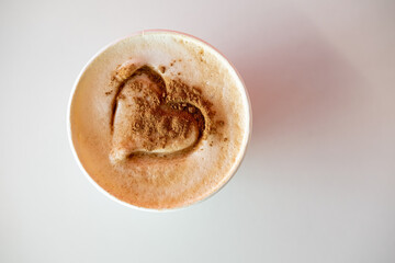 Cappuccino with cinnamon and a drawn heart on lush foam. Invigorating, aromatic morning drink. View from above.