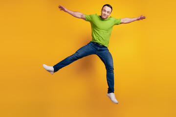 Fototapeta na wymiar Portrait of funky dreamy positive cheerful guy jump raise hand on yellow wall