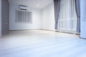 Empty room or bedroom at night. Interior inside house consist of wooden laminate floor, white gray wall, air conditioner, curtain and adjusting vertical blinds. New clean look modern for background.
