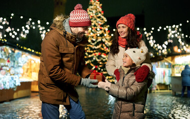 family, winter holidays and celebration concept - happy mother, father and little daughter with...