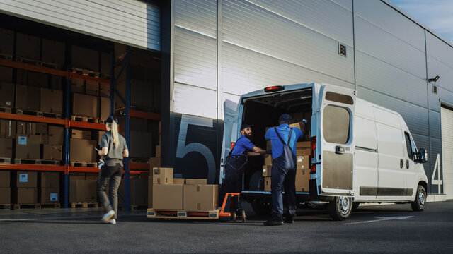 Outside of Logistics Distributions Warehouse With Manager Using Tablet Computer, Workers Start Loading Delivery Truck with Cardboard Boxes. Online Orders, Purchases, E-Commerce Goods.