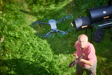 Old senior man upset by a flying drone over his garden. The concept of spying on neighbors and...