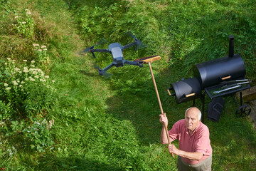 Old senior man upset by a flying drone over his garden. The concept of spying on neighbors and...