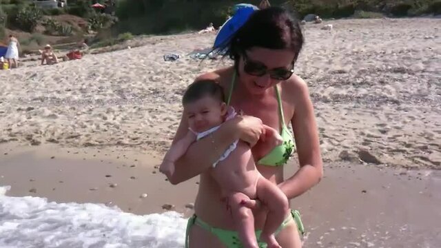 Young baby at the seaside making her first contact with water