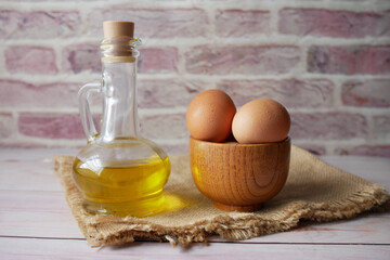 close up of eggs in a bowl and cooking oil on table 