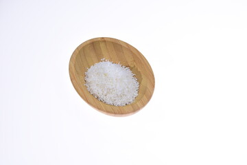 Coconut shavings in a wooden bowl against a white background. Food.