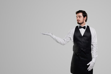 Elegant waiter pointing aside on blank space