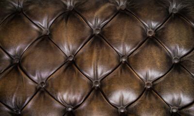 Shiny brown Chesterfield leather surface of an old couch