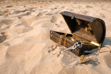 Open wooden chest with treasures on sand, space for text