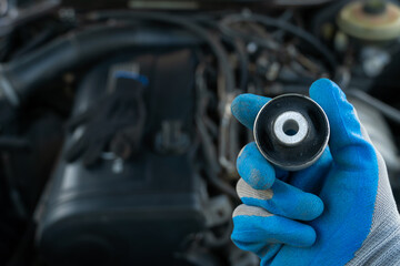 master in glove holds lever silent block in his hand against background of engine. rubber metal...