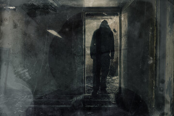 Fototapeta na wymiar A double exposure of a scary hooded figure standing in the doorway of a ruined building. With a grunge, texture vintage edit.