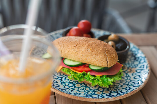 Close-up picture of sandwich on a plate. Breakfast concept. Sandwich with cheese, tomato, cucumber and lettuce served as breakfast or fast snack on a plate on a wooden table, copy space