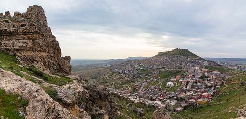 トルコ　丘から見える山の斜面に広がるマルディンの旧市街の街並みと山頂に立つマルディン城と夕焼け空