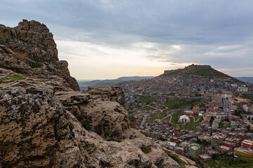 Fototapeta na wymiar トルコ　丘から見える山の斜面に広がるマルディンの旧市街の街並みと山頂に立つマルディン城と夕焼け空