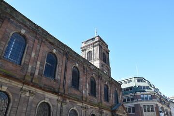 Looking up at a traditional old brick building with a clear blue sky background. 