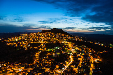 Fototapeta na wymiar トルコ　山の斜面に広がるマルディンのライトアップされた旧市街の夜景と山頂に立つマルディン城