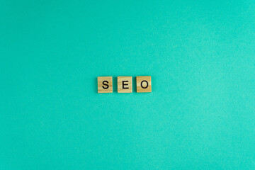 Word SEO. The phrase is laid out in wooden letters. Top view. Motivation. Blue background. Copy space