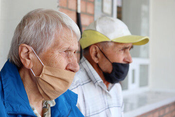 Elderly couple in masks sitting outdoor. Life in retirement, safety of senior people during...