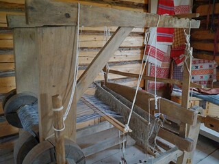 An old wooden loom in a wooden house built in the 19th century. Making fabric from yarn on a wooden loom.