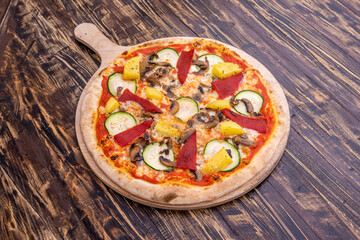 Vegan pizza with potato cheese, roasted red pepper, pineapple chunks, mushrooms and cucumber slices