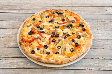 Vegan pizza with potato cheese with slices of black olives, slices of mushrooms, artichoke leaves and roasted peppers