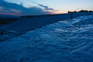 トルコ　夕暮れ時のヒエラポリス・パムッカレの鍾乳石と青い水面