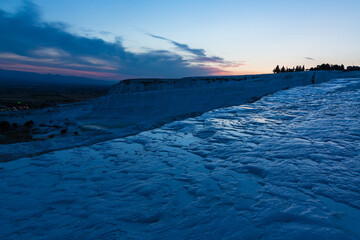 トルコ　夕暮れ時のヒエラポリス・パムッカレの鍾乳石と青い水面