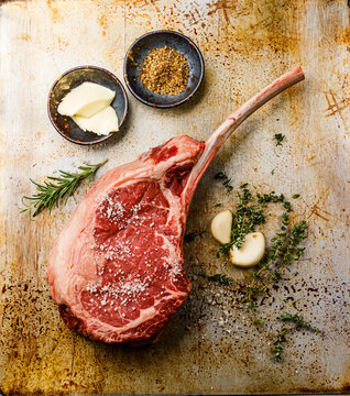 Raw fresh meat Tomahawk Steak and seasonings on baking sheet background