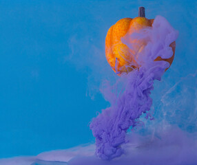 orange pumpkin with purple purple smoke on a blue background, abstract Halloween concept