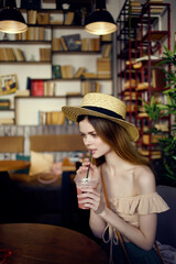 pretty woman sitting at a table with a drink in a cafe communication