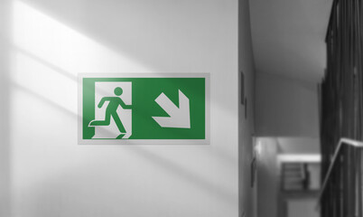 Emergency exit sign on a white wall. Interior with stairs. - obrazy, fototapety, plakaty