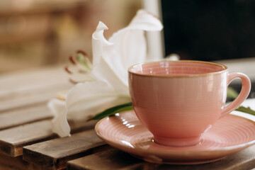 Laptop screen,pink cup and a lily flower on the wooden table.A modern workplace.Business,e-learning, freelance, technology concept.Copy space for text.