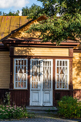 A partial view of an old wooden yellow house with white windows and door