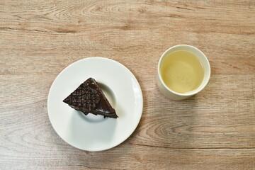 black forest cake with cream topping chocolate and hot tea cup on table