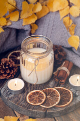 Autumn composition with aromatic candle, dry citrus, cinnamon. Aromatherapy on a grey fall morning, atmosphere of cosiness and relax. Wooden background close up