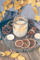 Autumn composition with aromatic candle, dry citrus, cinnamon. Aromatherapy on a grey fall morning, atmosphere of cosiness and relax. Wooden background close up