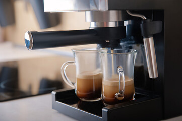 Two transparent cups coffee close-up front view. Home coffee maker and process of making coffee drink.