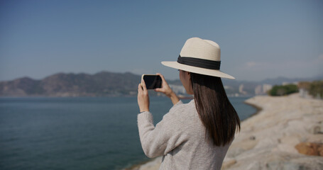 Woman use smart phone to take photo at landscape