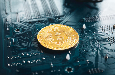 Gold bitcoin on a dark background on a printed circuit board. Cryptocurrency mining.