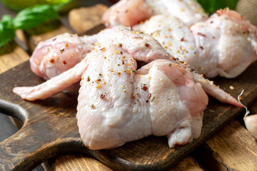 Raw chicken wings on a wooden board on a dark culinary background closeup	