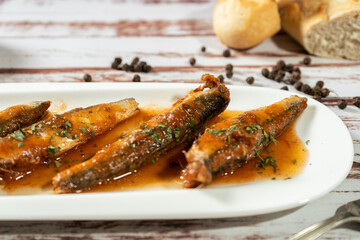Close-up of Sardines in tomato sauce and parsley served in a small white platter.
